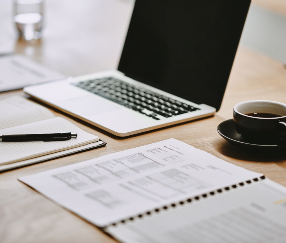 laptop, notebooks, and a cup of coffee on a wooden table
